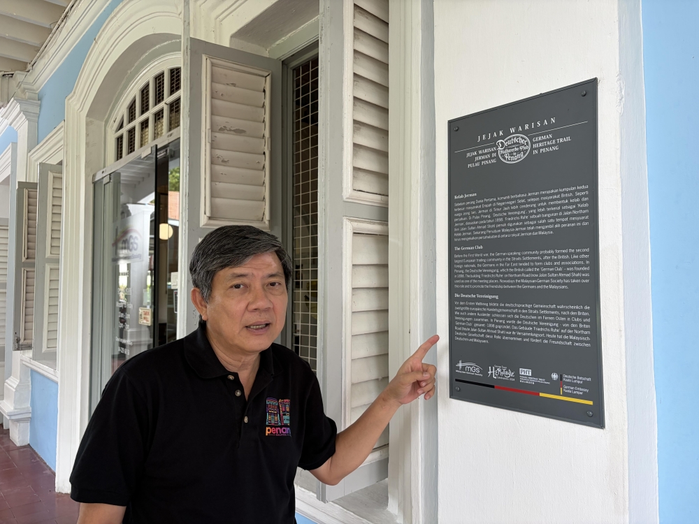 Clement Liang pointing out a plaque with information on MGS outside the building. — Picture by Opalyn Mok