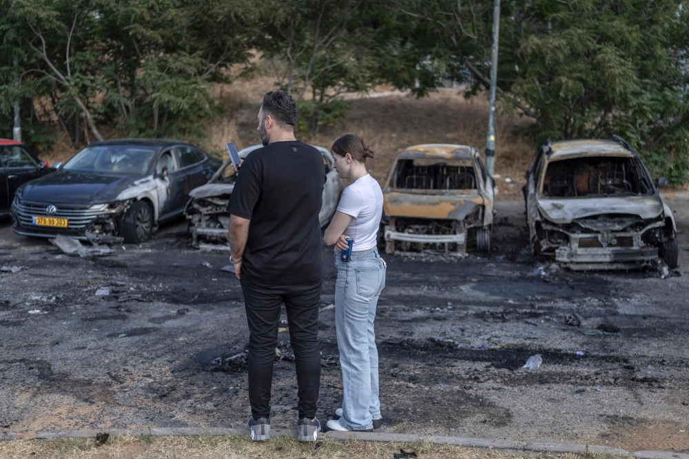 This picture taken on June 28, 2026 shows residents standing at the site of a car explosion in Holon on the outskirts of Tel Aviv. — AFP pic