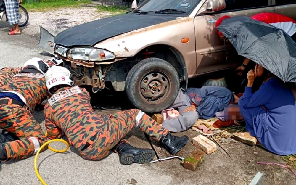 Firefighters rescue woman trapped under car as vehicle rolls forward while she opens gate in Ipoh home