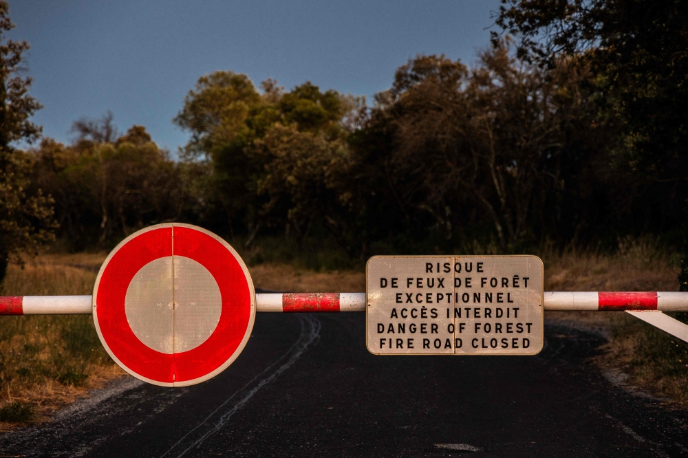 A barrier blocks a road to warn of extreme forest fire risk near Millas in the Pyrenees-Orientales department of southern France on July 5, 2026. — AFP pic