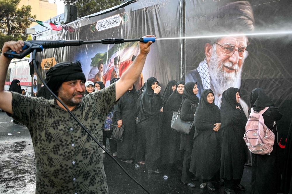 People are sprayed with water to cool off during the heat while queueing for food on their way to the Grand Mosalla in Tehran on July 5, 2026, for the funeral ceremonies of Iran’s slain supreme leader Ayatollah Ali Khamenei. — AFP pic