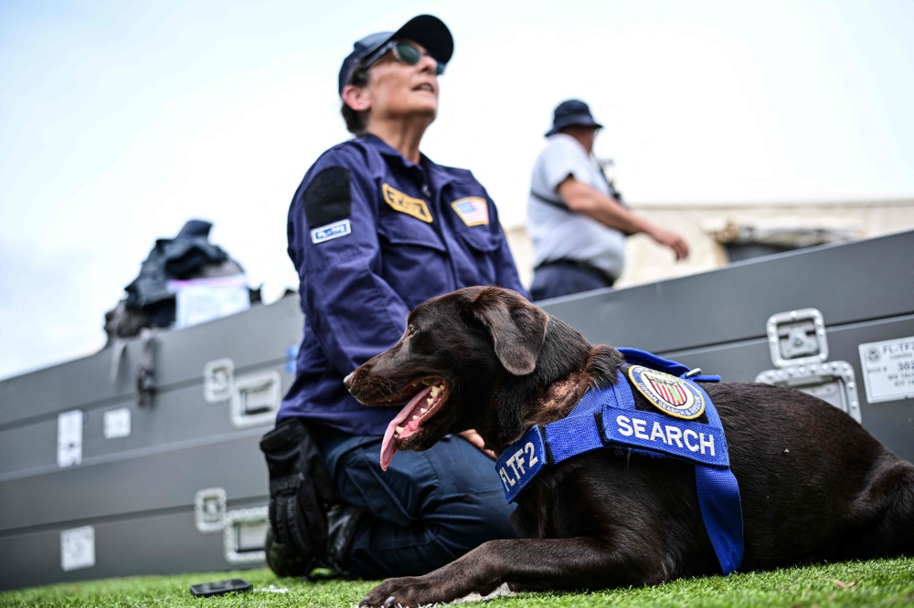 Silvya Arango of the Rescue Florida Task Force 2 team is seen with her labrador retriever dog Sisu, who participated in the rescue works, at a camp in Maiquetia, La Guaira state, Venezuela, on July 4, 2026, ten days after twin earthquakes. — AFP pic