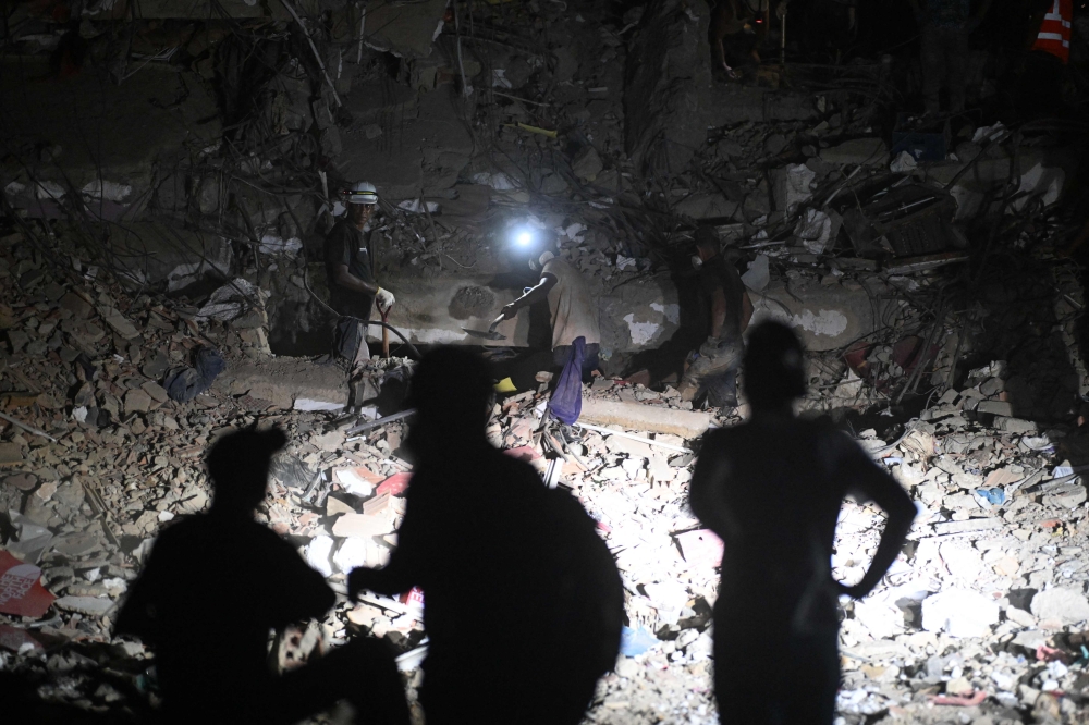 Rescuers and volunteers work with headlamps during nighttime operations on the rubble of a collapsed building in Caraballeda, La Guaira state, Venezuela on July 7, 2026. — AFP pic