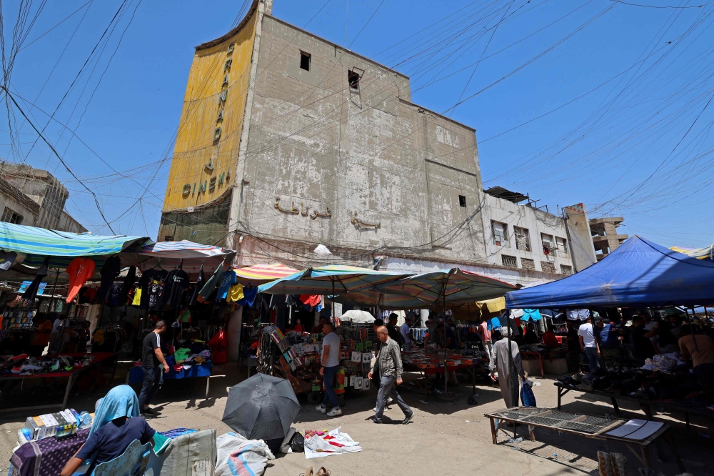 Street vendors gather outside the faded facade of the Granada Cinema, an early 1940s landmark, in the Bab al-Sharqi district of central Baghdad on May 26, 2026. — AFP pic