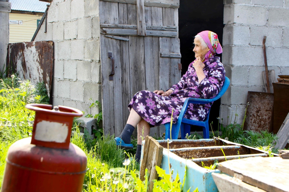 An elderly woman sits in a yard next to a gas cylinder in the town of Shchuchinsk. — AFP pic