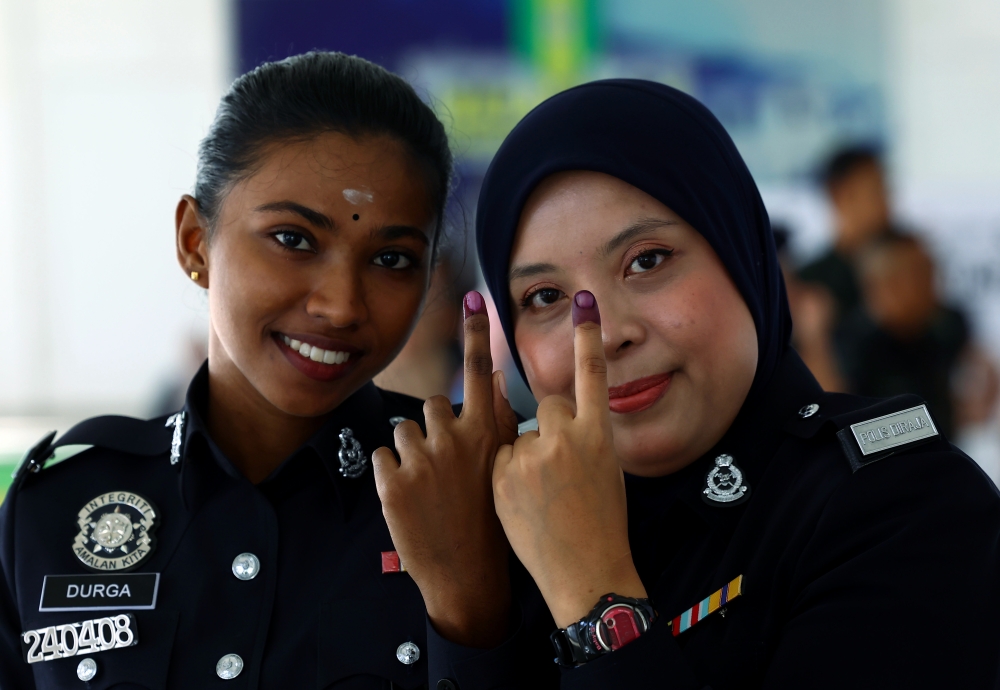 Corporal Masnoor Muzaryi Suzila Rosli and Constable M. Durgashini (left) show their inked fingers after casting their early votes in the 16th Johor state election at the General Operations Force Battalion 5 camp in Simpang Renggam, Kluang, on July 7. — Bernama pic