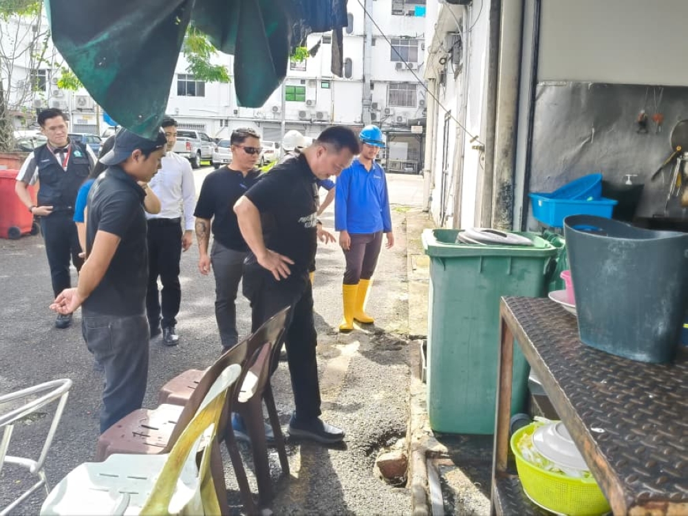 Miri councillor and chairman of its City Services Standing Committee Kelvin Chia inspects a drain outside an eatery. — The Borneo Post pic