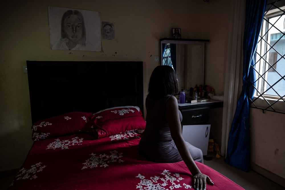 Sandra, a hairstylist, sits on a bed inside her home in Benin City on May 21, 2026, after returning to Nigeria in 2021 following her trafficking overseas. — AFP pic 