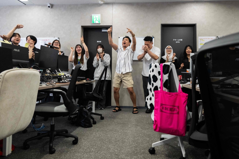 Employees chant work targets during a daily meeting, at the Global Partners office in Tokyo. — AFP pic