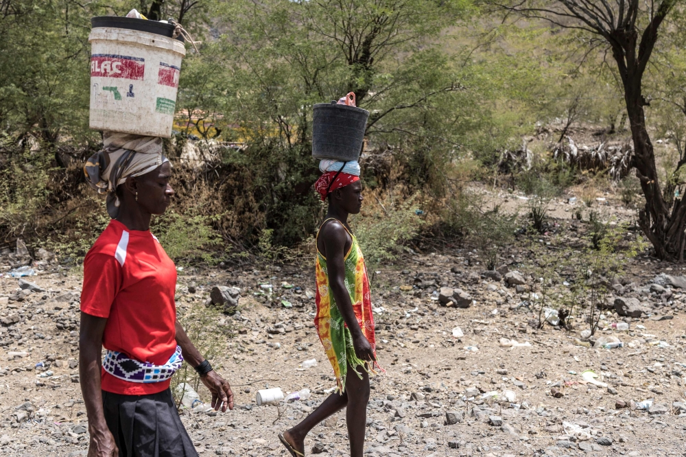 Women balance buckets on their heads as they walk to the beach to mine sand for commercial sale in Charco, on May 20, 2026. — AFP pic