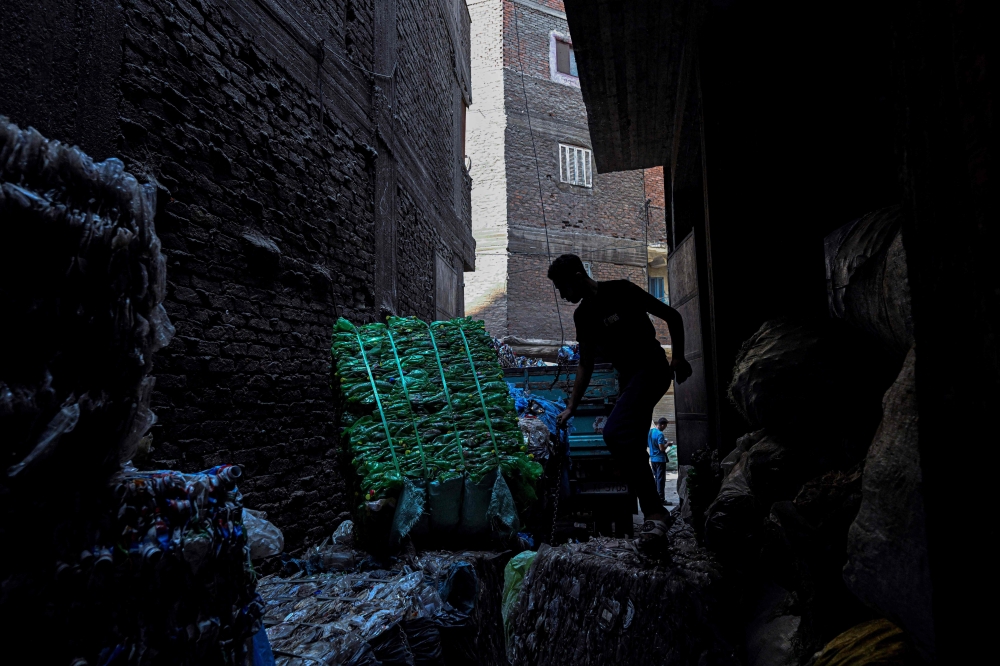 Egyptian workers load bails of plastic for recycling on a truck at the garbage city in the Manshiyet Nasser neighbourhood in Cairo on July 6, 2026. — AFP pic
