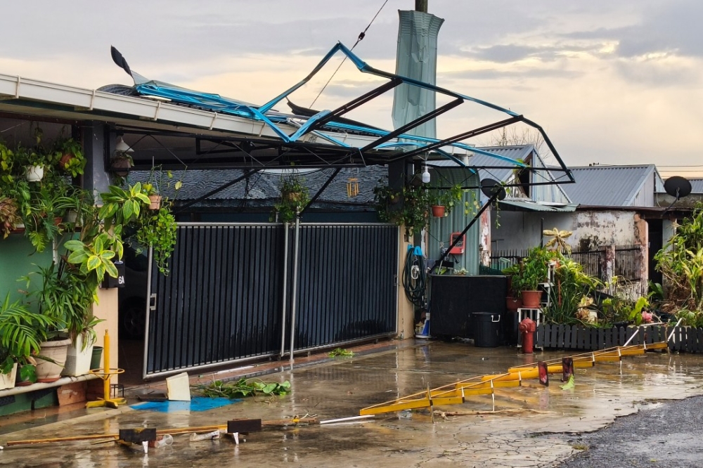 A car porch and awning severely damaged after being torn apart by strong winds during a heavy downpour in Sibu Jaya on Saturday. — The Borneo Post pic