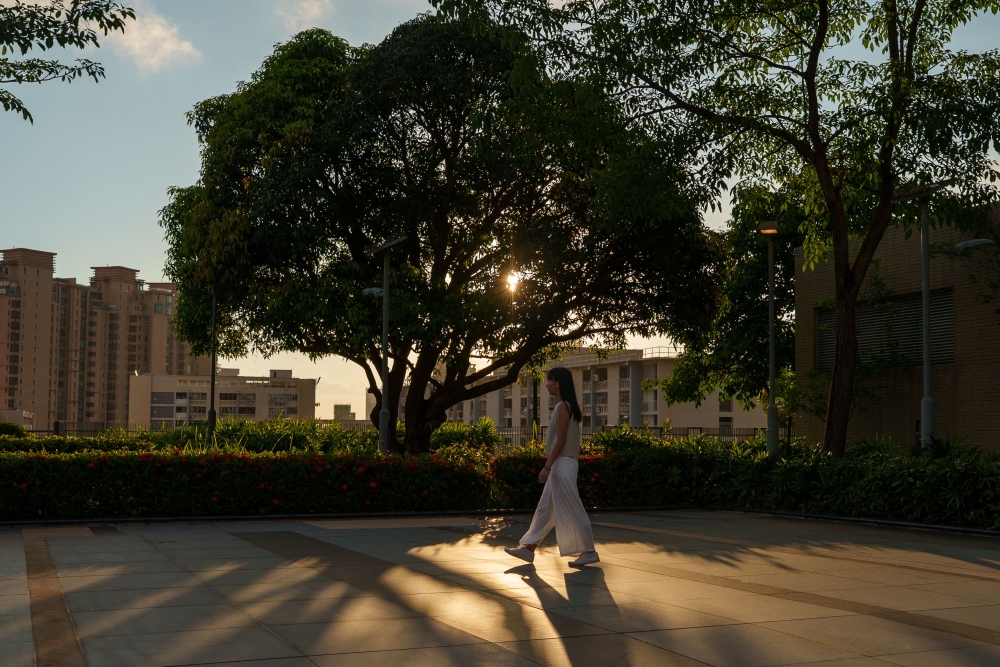 Jessie, a survivor of sexual violence, walks into the shadow of a tree at a park in Hong Kong on June 22, 2026. — AFP pic