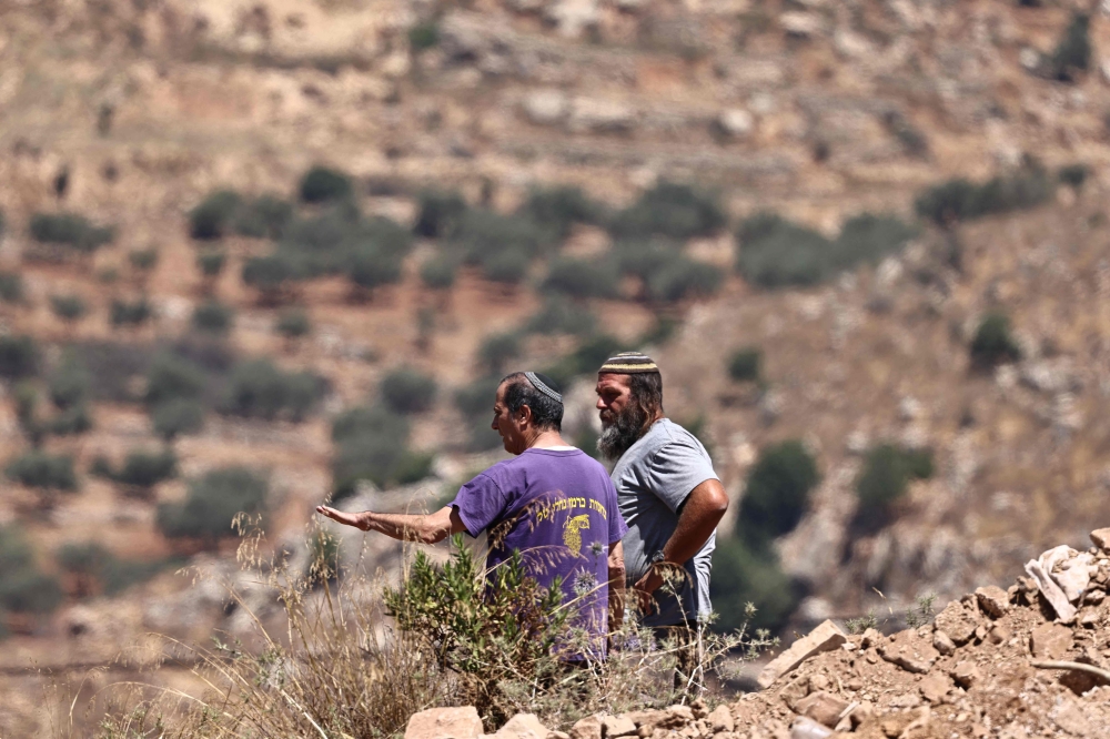 Israeli settlers stand near the al-Tireh neighbourhood at the western entrance of the city of Ramallah, in the occupied West Bank on July 14, 2026. — AFP pic
