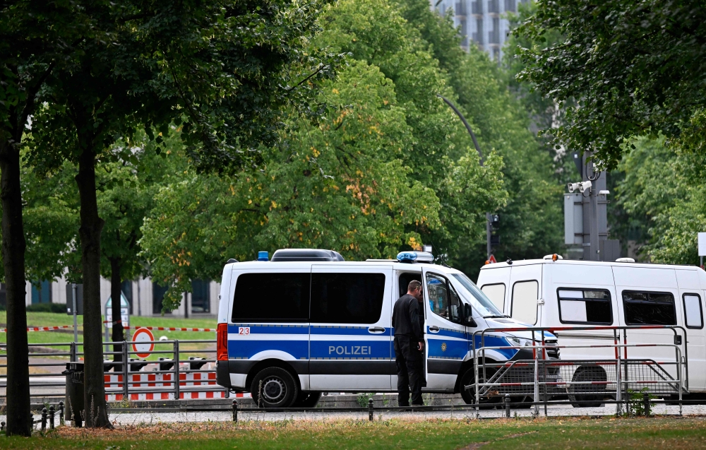 Police stand guard on July 26, 2026 in the area where a car was driven into people killing one person and injuring 16 before crashing on a tree in the Tiergarten park on the outskirts of the Christopher Street Day (CSD) parade in Berlin held the day before. — AFP pic