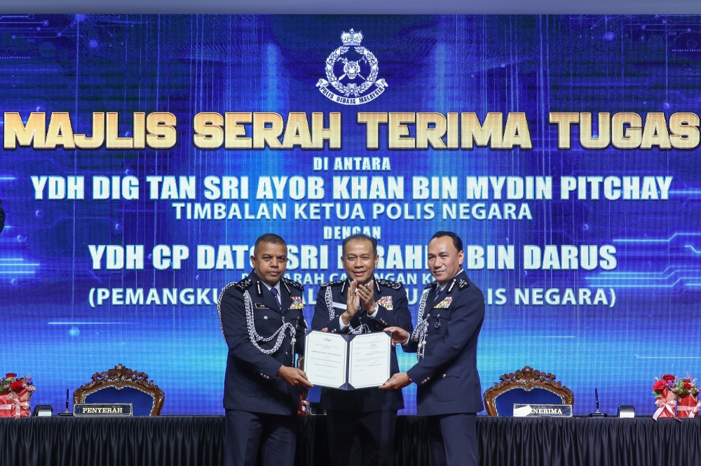 Deputy IGP Tan Sri Ayob Khan Mydin Pitchay (left) hands over duties to successor Datuk Seri Ibrahim Darus (right) as IGP Tan Sri Mohd Khalid Ismail (centre) looks on during the handover and farewell ceremony at Pulapol, Kuala Lumpur, July 26, 2026. — Picture by Yusof Isa