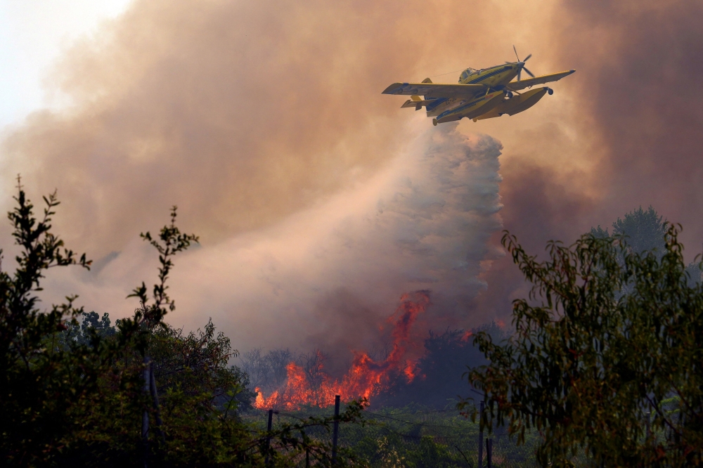 An Air Tractor AT-802F Fire Boss aircraft dumps water over a wildfire burning near San Martin de Valdeiglesias near Madrid on July 26, 2026. — AFP pic