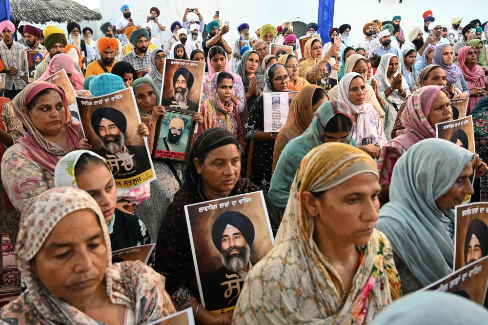 This photograph taken on July 14, 2026 shows people holding portraits of late human rights activist Jaswant Singh Khalra during a prayer ceremony for the people who allegedly disappeared after police detention during separatist insurgency in 1980s and early 1990s, in Harike Pattan in Punjab's Tarn Taran district. Across Punjab, Sikh religious bodies and political groups have been hosting Satluj film screenings in temple courtyards, community halls and village squares with viewer numbers swelling. — AFP pic