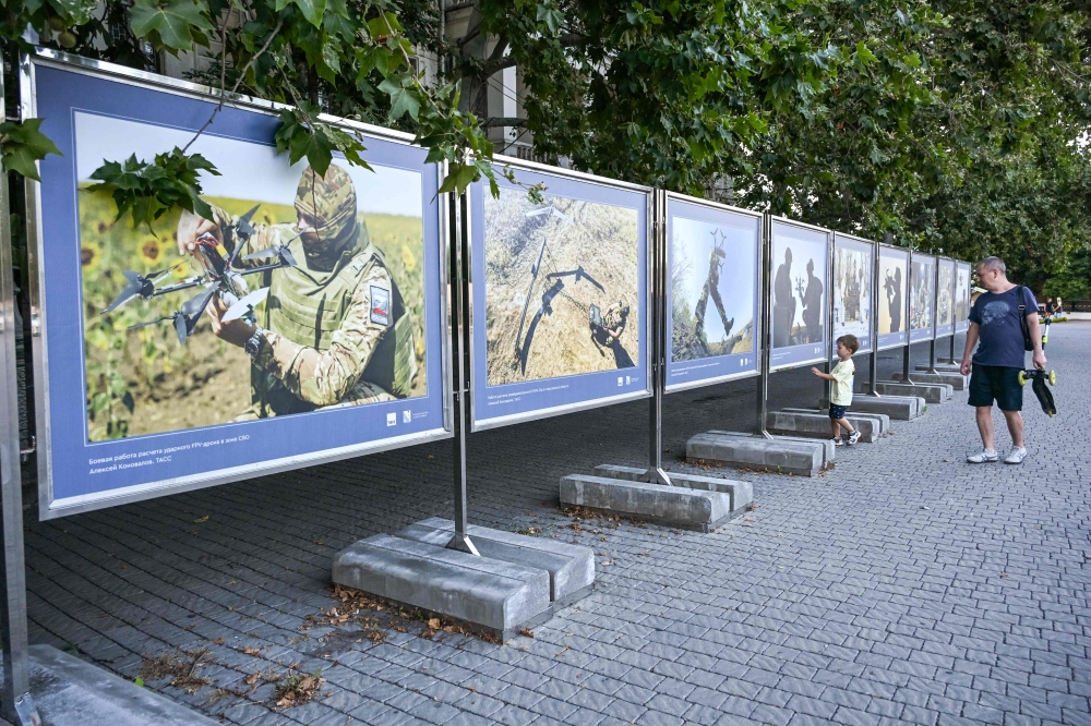 A man looks at photographs of an exhibition dedicated to drone-operating troops in central Sevastopol on July 22, 2026. — AFP pic