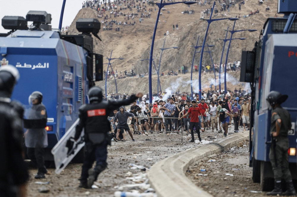Moroccan security forces confront migrants attempting to cross into Spain’s North African enclave of Ceuta during clashes near the town of Fnideq on the Morocco-Spain border on July 31, 2026. — AFP pic