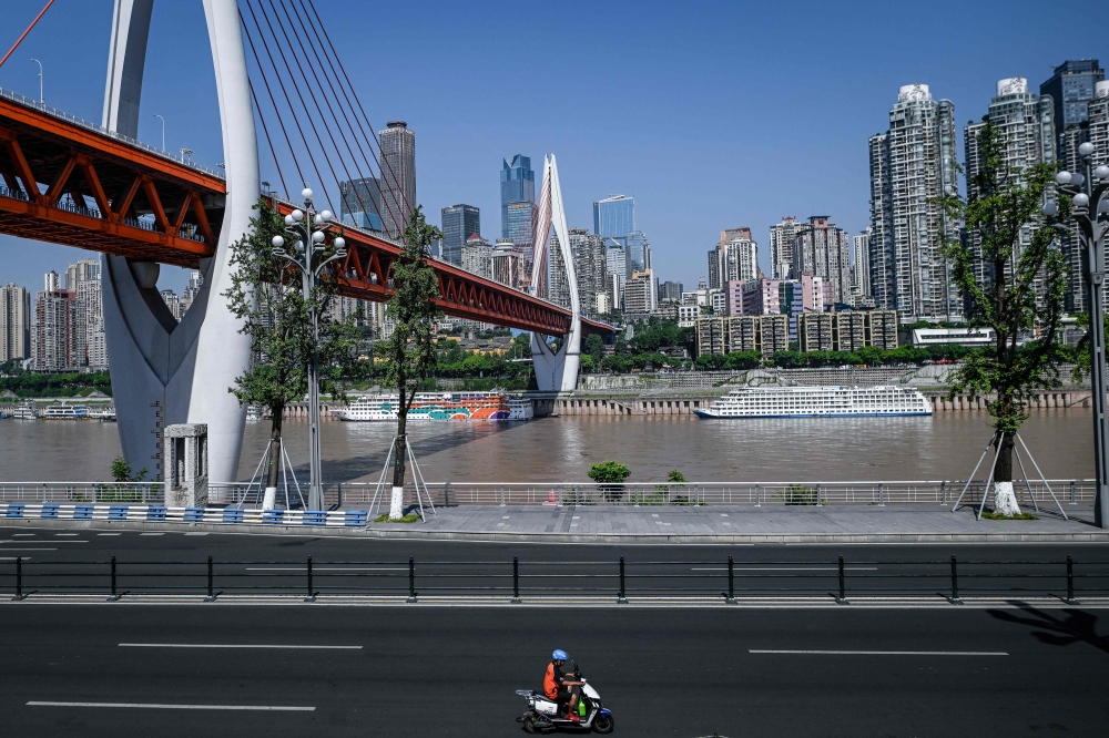 A man rides his motorcycle along a street in Chongqing July 21, 2026. — AFP pic