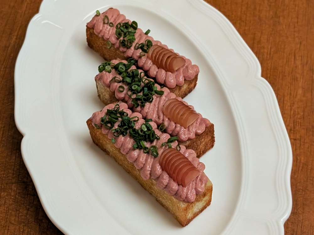Chicken ‘pâté’ is served on little batons of toast, and topped with chives and pickled grapes. — Picture by Ethan Lau