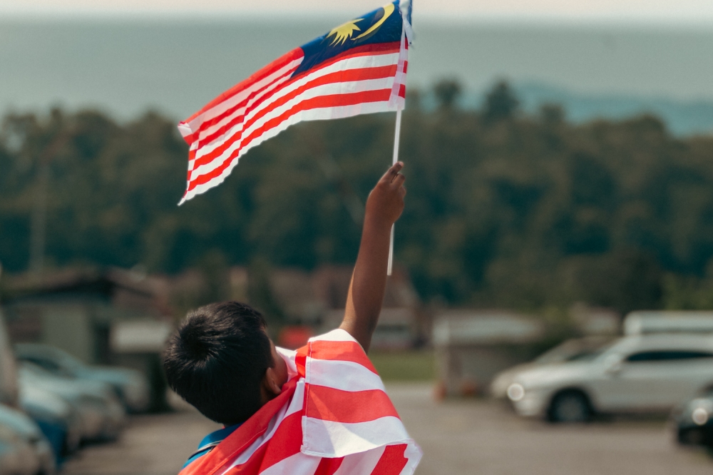 Boy waving the national flag in a park at Cheras,August 10,2022—Picture by Devan Manuel