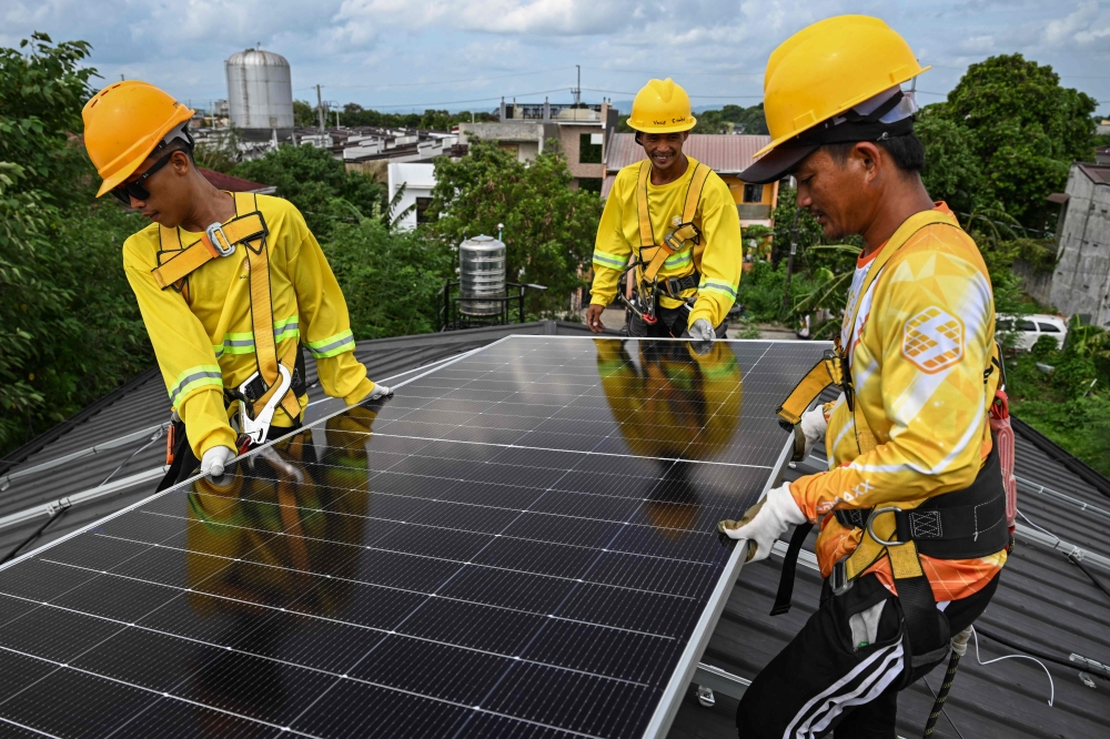 Workers install solar panels on a roof in Carmona, Cavite on July 9, 2026. — AFP pic