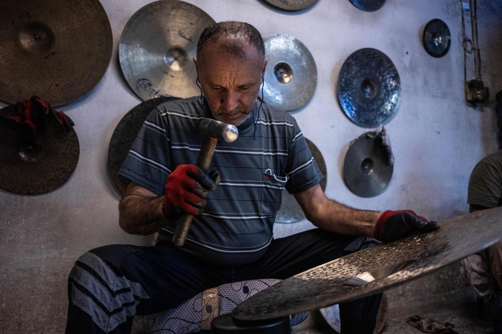 A worker hammers a cymbal at a workshop in Istanbul on July 30, 2026. — AFP pic