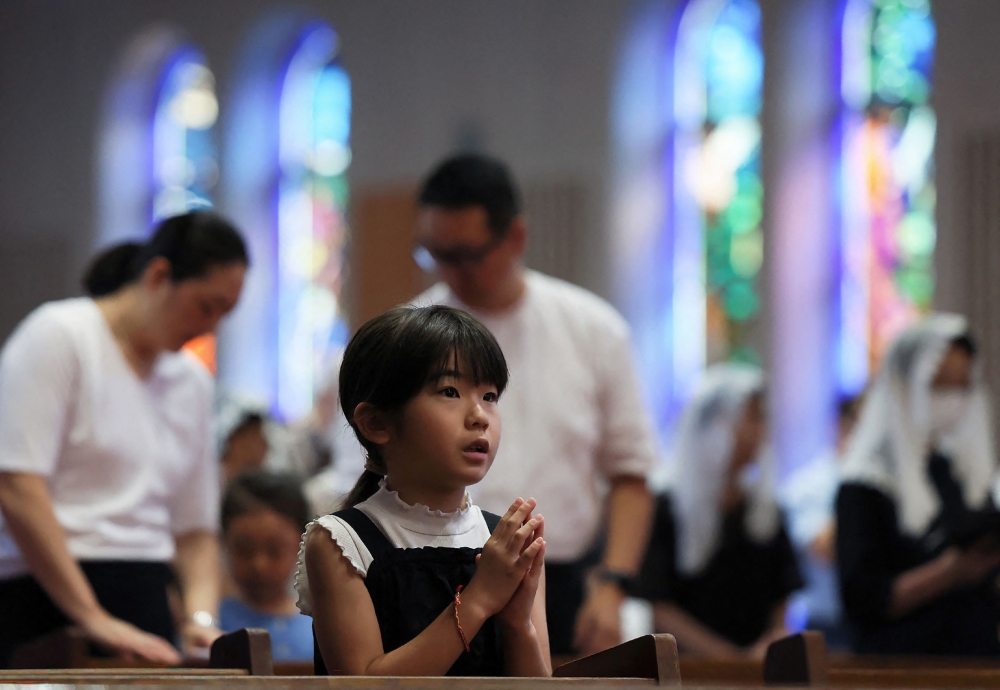A girl prays during mass at Urakami Cathedral in Nagasaki on August 9, 2026, marking the 81st anniversary of the atomic bombing. — JIJI Press/Japan OUT/ AFP pic