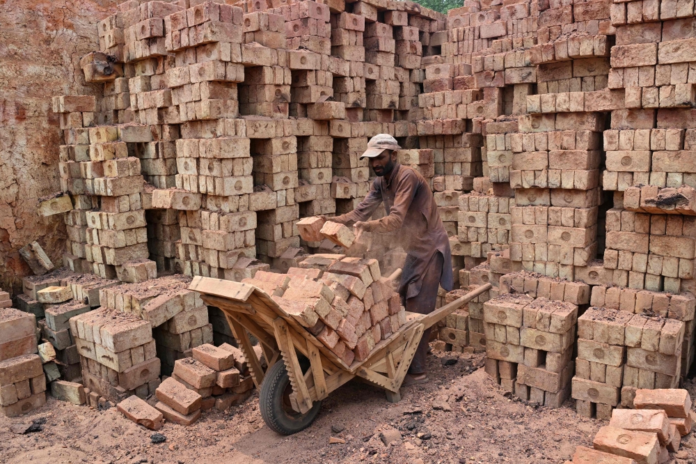 A man works at a brick kiln in Sheikhupura, in Pakistan痴 Punjab province on July 20, 2026. Below dark plumes billowing from smokestacks, brick workers on a kiln in Pakistan's Sheikhupura district crush coal through small holes into the fiery chambers below. Despite the scorching sun and dust filling the hot air, they stay on the heated surface for hours at a time, trapped in a cycle of debt, extreme heat, and deteriorating health, with rising global temperatures amplifying the risks. — AFP pic