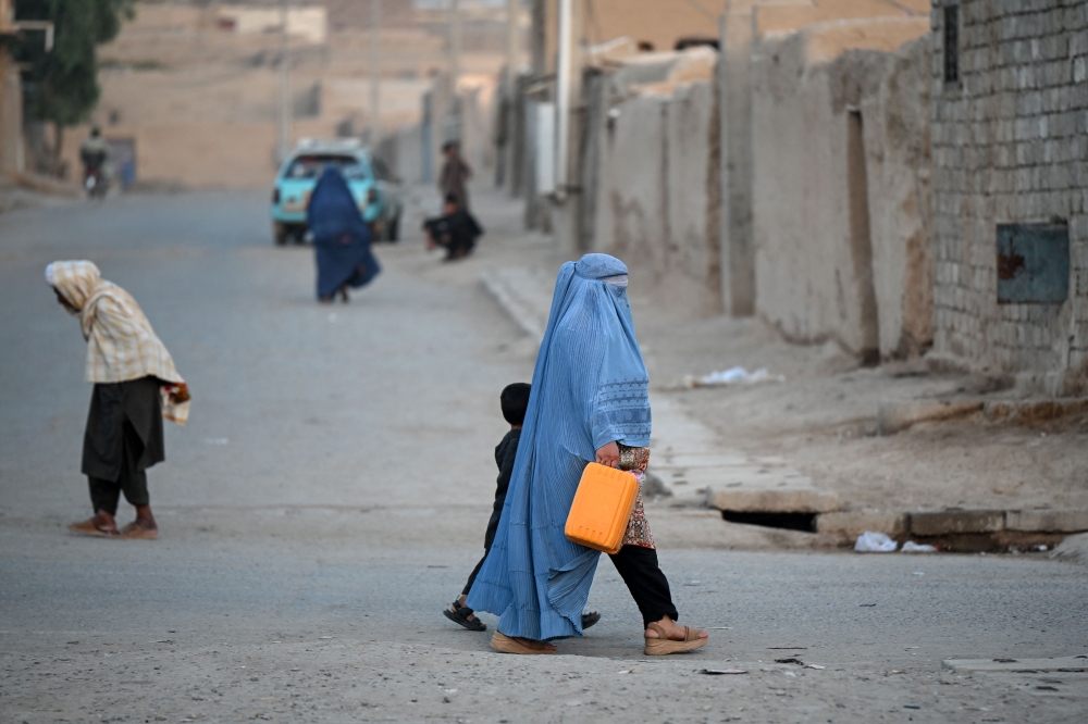 An Afghan burqa-clad woman walks along a street in the 7th district of Afghanistan's Kandahar on August 11, 2026. — AFP pic