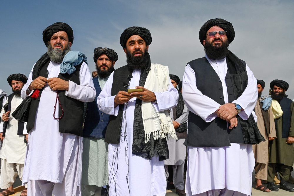 This file picture shows Taliban spokesman Zabihullah Mujahid (centre) speaking to the media at the airport in Kabul on August 31, 2021, after the US pulled all its troops out of the country. — AFP pic