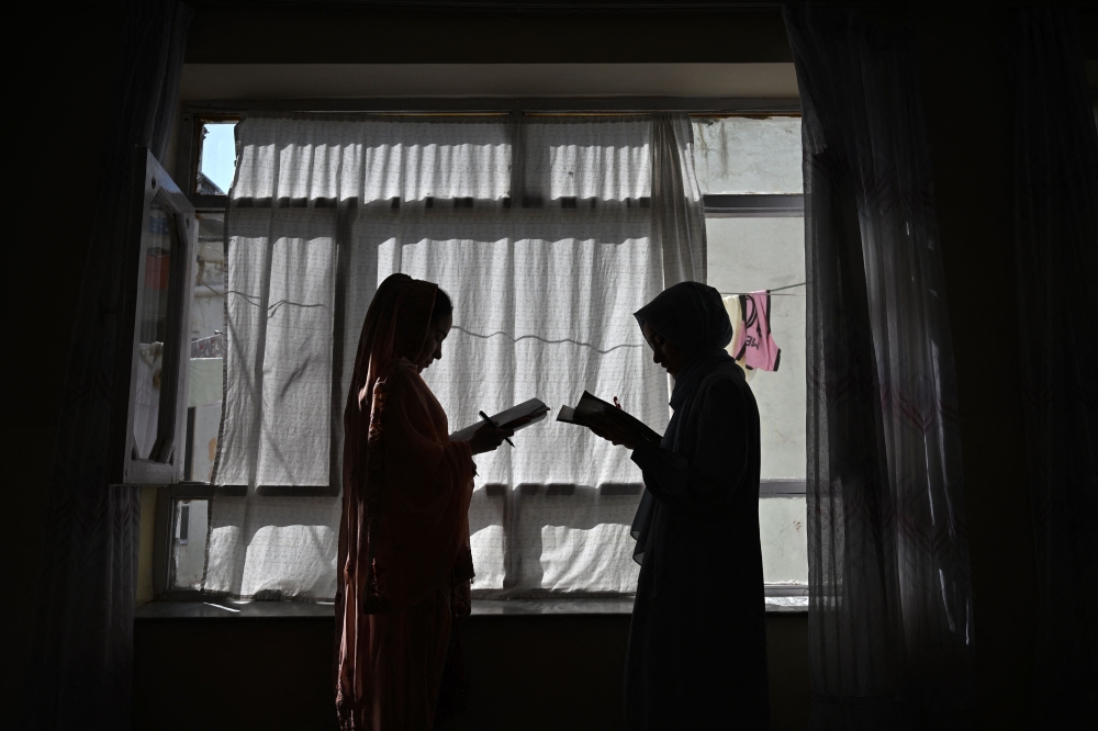 This photograph taken on August 6, 2026 shows Afghan girls attending a lesson by their father at their residence in Kabul. — AFP pic