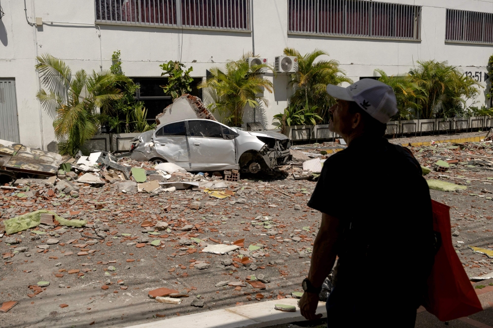 A man stands next to a destroyed car following an earthquake in Pereira, Colombia on August 11, 2026. Colombian volunteers and rescuers cleared rubble with their bare hands to search for survivors early on August 11 after the country's strongest earthquake in a decade killed at least 169 people and smashed dozens of buildings. — AFP pic