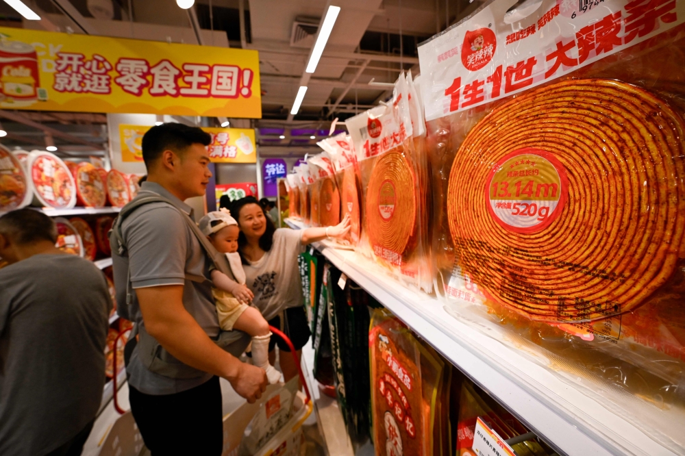 Customers selecting a packet of spicy strips measuring 13.14 metres in length at a market in Changsha, in China's central Hunan province. — AFP pic