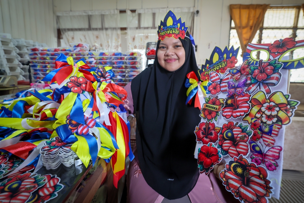 A trader displays a collection of Jalur Gemilang ribbons she sells online, in Kampung Paya Senang. — Bernama pic