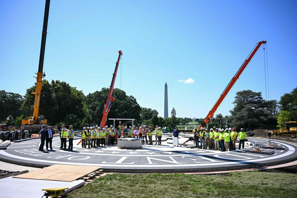 Workers look on at the construction site of a helipad as US President Donald Trump speaks to the press on the South Lawn of the White House in Washington, DC, on August 19, 2026. — AFP pic