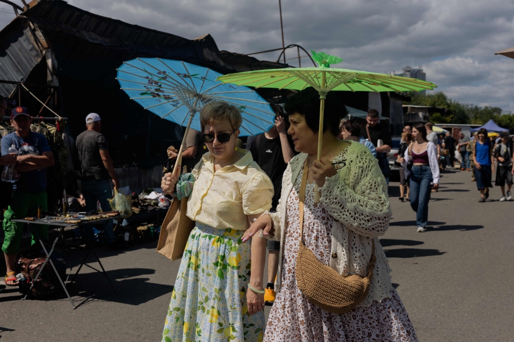 Women holding umbrellas to protect themselves from the sun walk along a damaged street market following strikes in Petrivka, one of Kyiv’s neighborhoods on August 9, 2026, amid the Russian invasion of Ukraine. — AFP pic 