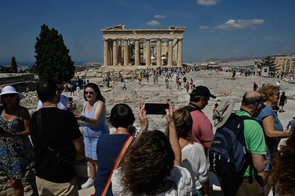 Tourists take photos and selfies at the Parthenon temple on the Acropolis in Athens, June 14, 2023. — AFP pic