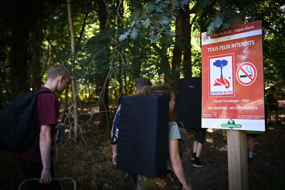 Visitors pass ‘All fires prohibited’ sign as Fontainebleau forest reopens after July wildfire. — AFP pic