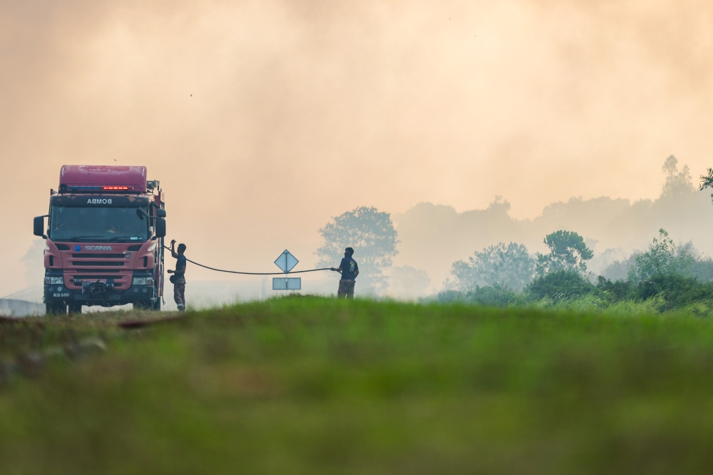 Fire and Rescue Department personnel battling the blaze along the Punggai–Sebana Cove bypass. — Bernama pic
