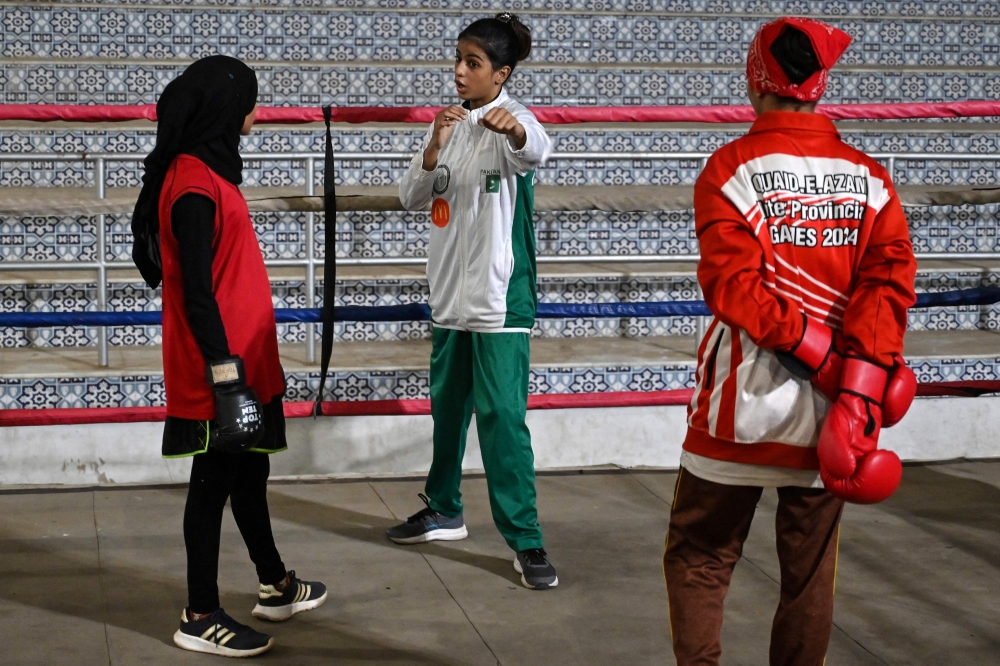 This photograph taken on July 7, 2026 shows a professional boxer Aliya Soomro (centre) interacting with junior boxers during a sparring session at a local boxing club in Karachi’s Lyari town. — AFP pic 