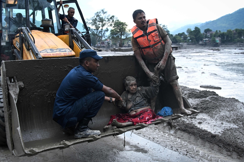Rescuers use an excavator to transport a flood survivor following flash floods and a landslide in Devghat, Nepal’s Nuwakot district, on August 26, 2026. — AFP pic