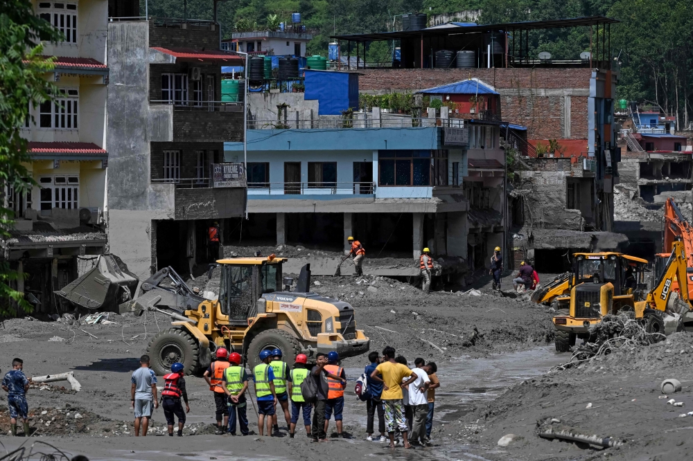 Volunteers use bulldozers to clear mud and debris along a road after flash floods at Trishuli in Nepal's Nuwakot district on August 27, 2026.  — AFP pic