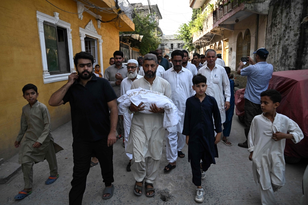 A man carries the body of a newborn who died in a fire at the maternity ward of the Pakistan Institute of Medical Sciences in Islamabad during a funeral in Rawalpindi on August 26, 2026. — AFP pic