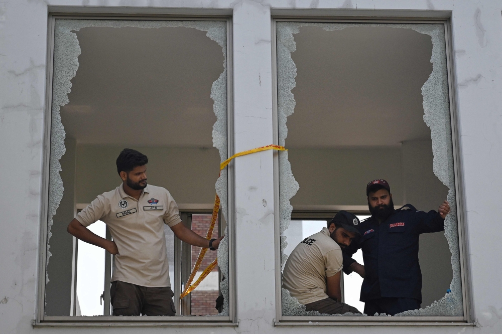 Police officers look through shattered windows after a fire at the maternity ward of the Pakistan Institute of Medical Sciences Hospital in Islamabad on August 26, 2026, which killed 14 newborns. — AFP pic