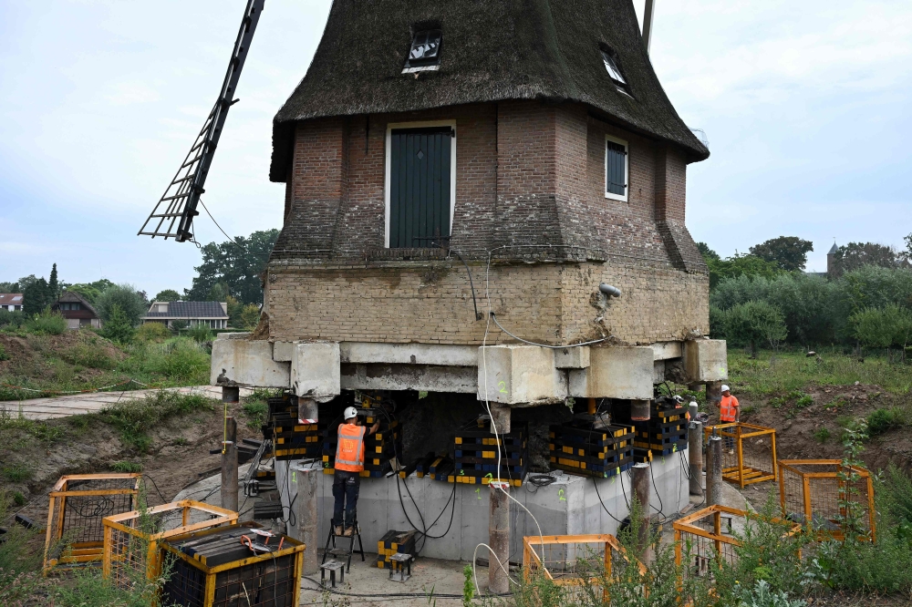 Workers take part in lifting a 250‑year‑old windmill. — AFP pic