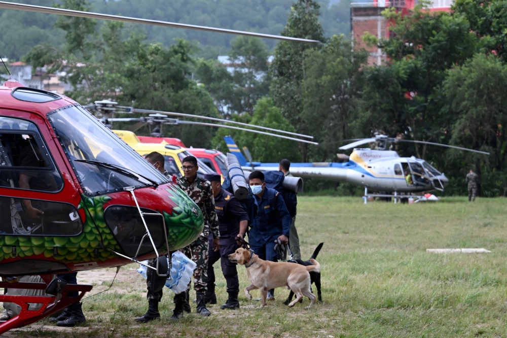 Security personnel with sniffer dogs board a helicopter bound for the flood-affected Mailung valley from Trishuli camp in Nepal’s Nuwakot district on August 29, 2026.  — AFP pic