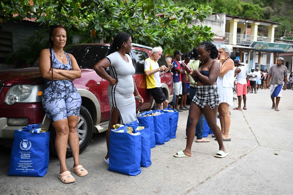 Venezuelans stand after receiving World Food Programme donations in Chichiriviche de la Costa, La Guaira state as many survive on a monthly minimum wage equivalent to US$0.16 (RM0.67), plus government subsidies that can reach US$240 (RM1,010) per month – still far short of the estimated US$730 (RM3,073) needed to buy basic food necessities for a family of five. — AFP pic